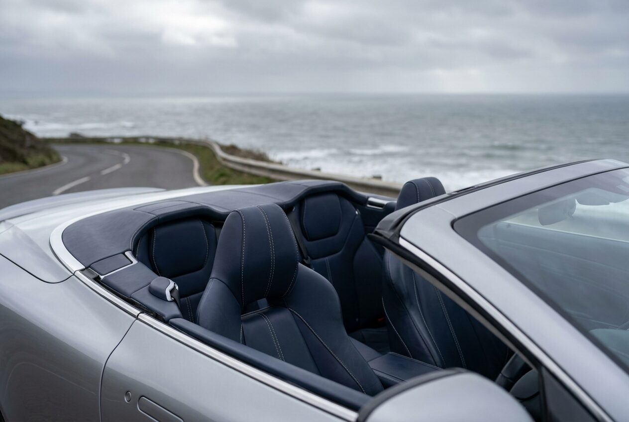Open cockpit with navy leather seats and the fabric roof stowed flush