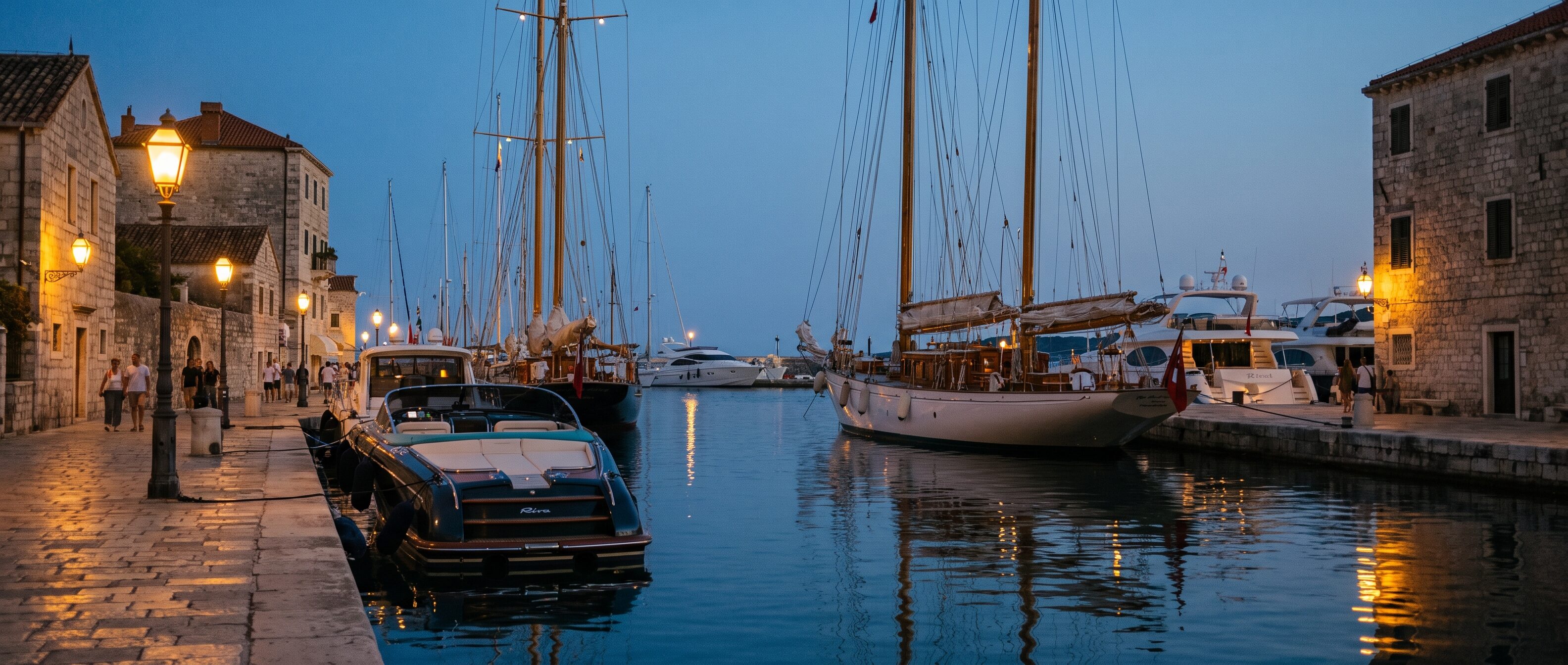 Yachts moored along a stone quay at dusk