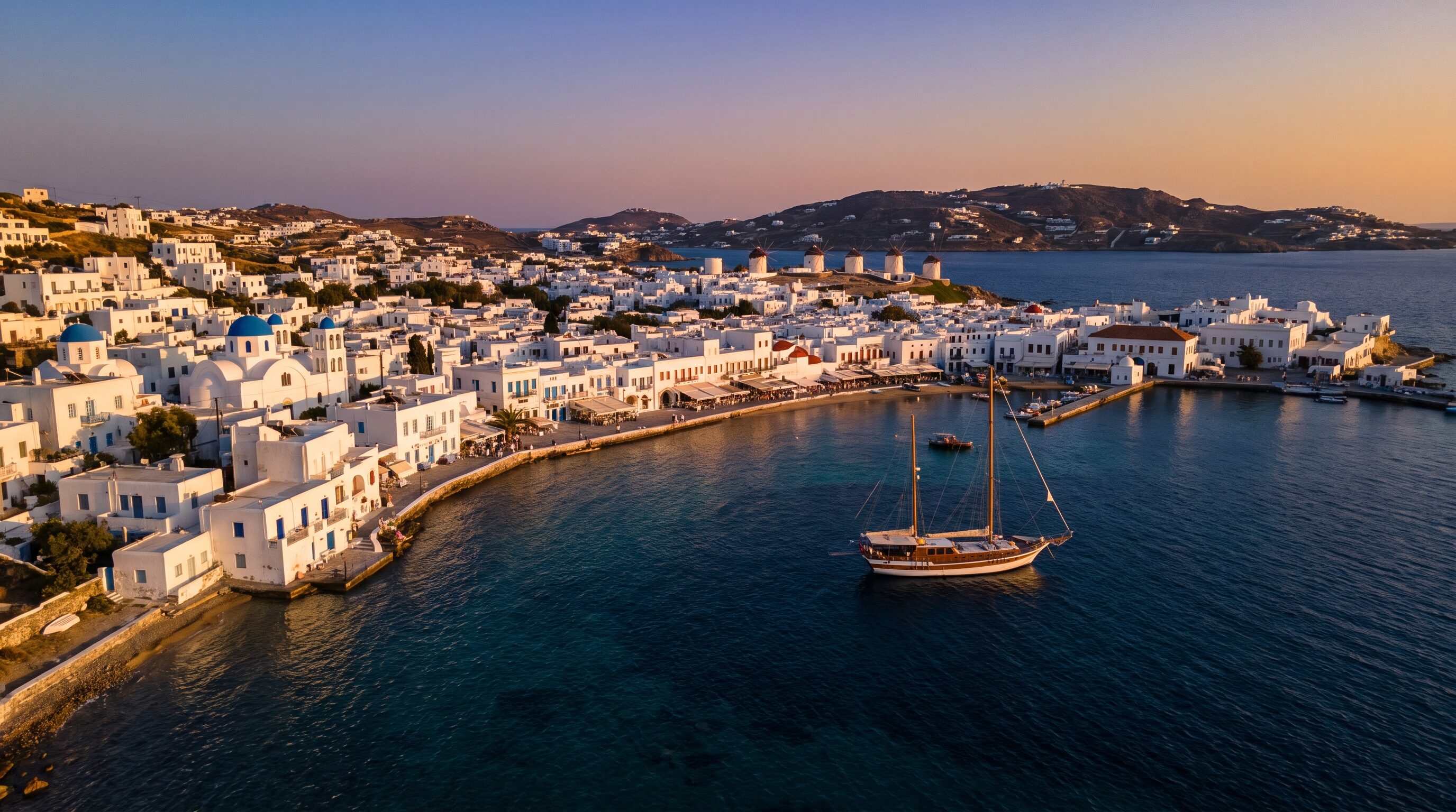 Whitewashed Cycladic village above an indigo Aegean bay at sunset